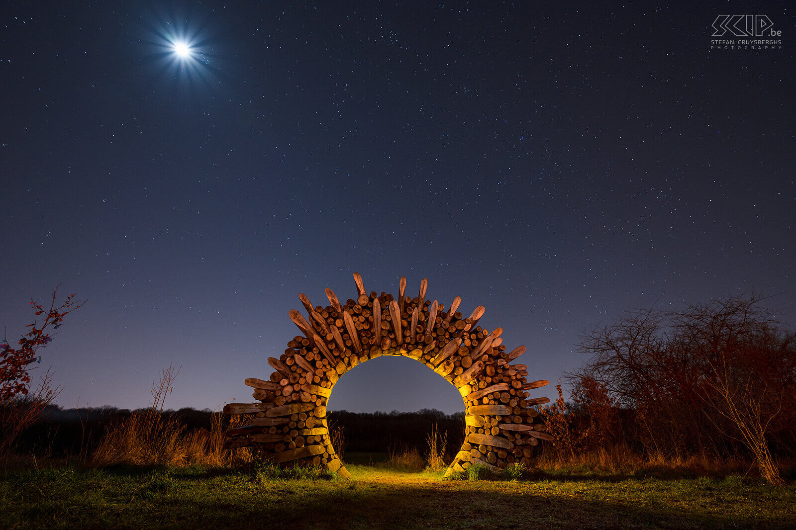 Hageland by night - Full moon at the Chartreuzenforrest gate in Holsbeek Full moon and a beautiful starry sky at the gate on the edge of the Chartreuzenforrest, located in Holsbeek and Lubbeek. The wooden gate is a beautiful work of art in the shape of a sun. I tried to create some atmosphere by doing some lightpainting. Stefan Cruysberghs